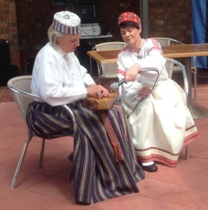 Two ladies in Latvian National costume playing the kokle, a Latvian musical instrument